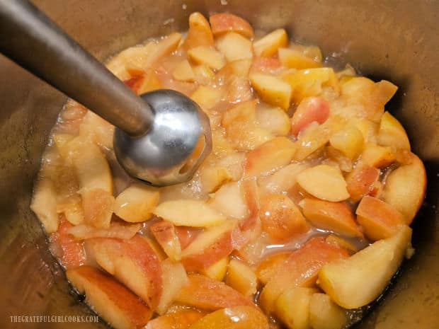 An immersion blender is used to purée the apples.