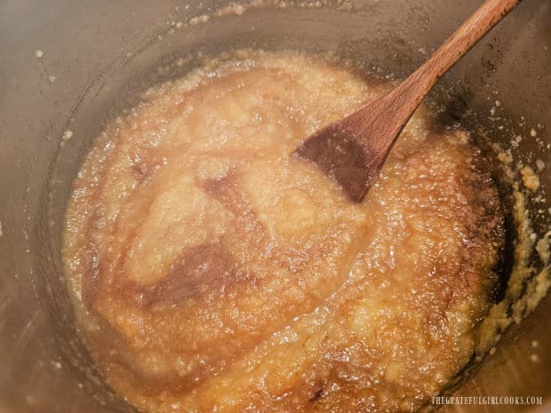 Applesauce is stirred, then cooked for a couple minutes after adding sugar and spices.