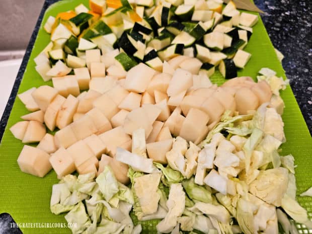 Zucchini, potatoes and cabbage are chopped before they are adding to the soup.