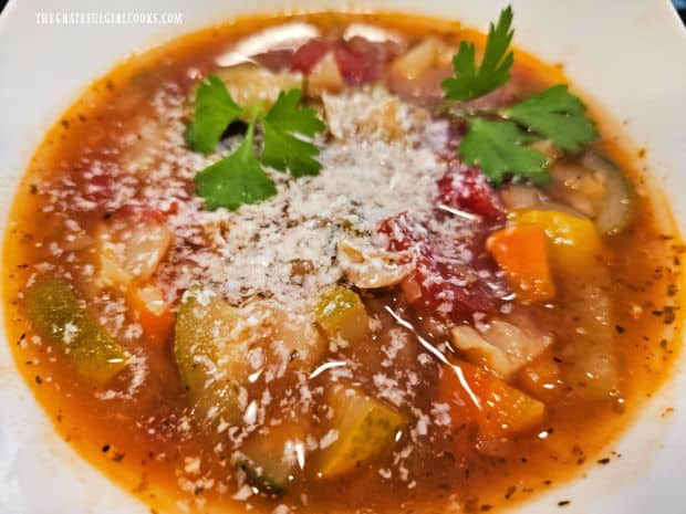 A bowl of Instant Pot Vegetable Soup, topped with Parmesan cheese and fresh parsley leaves.