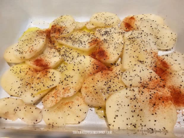 Potato slices are covered in melted butter/oil, seasoned with spices and layered in baking dish.