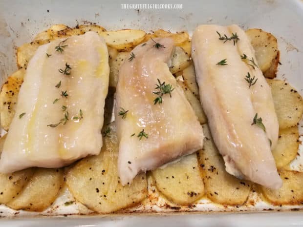 Cod fillets are drizzled with butter/oil and thyme and placed on top of roasted potato slices.
