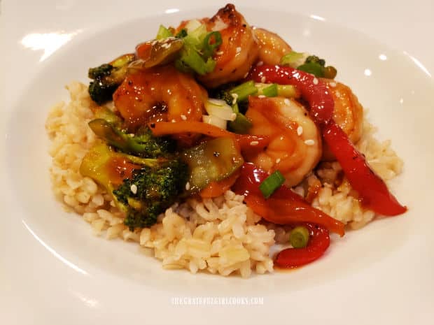 A white bowl with shrimp and broccoli stir-fry served on top of brown rice.