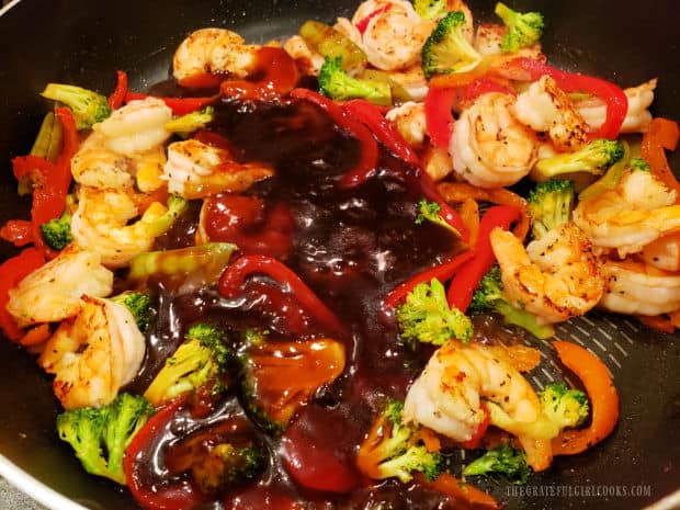Asian sauce is combined with the veggies and shrimp in the skillet.