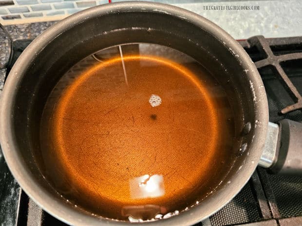 Apple cider (or juice) is simmered in a medium saucepan.