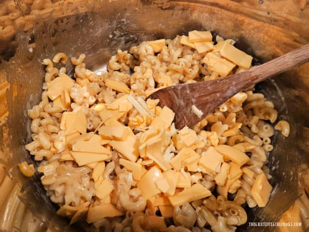 American cheese (in pieces) is stirred into the cooked macaroni.