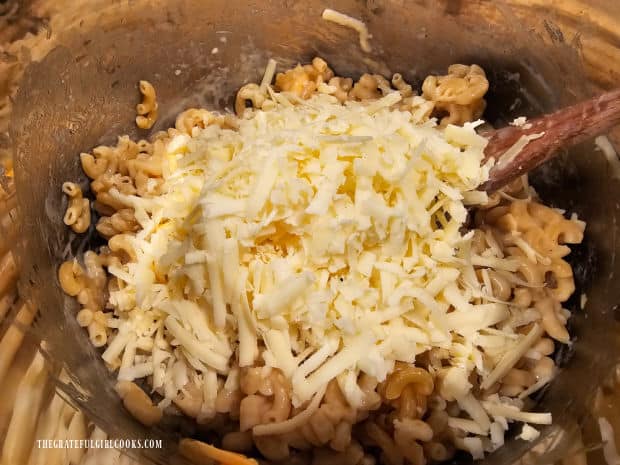 Grated white cheddar is added and stirred into the pasta, to combine and melt.