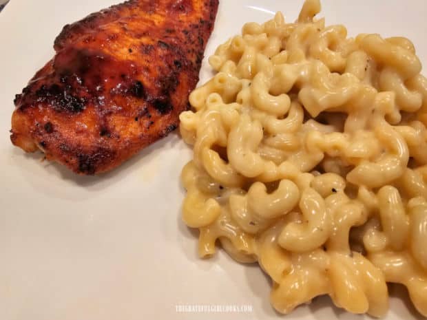 The Instant Pot macaroni and cheese is served with BBQ chicken on a white plate.