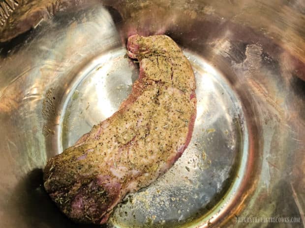 Seasoned pork tenderloin is seared on all sides in oil in the Instant Pot.