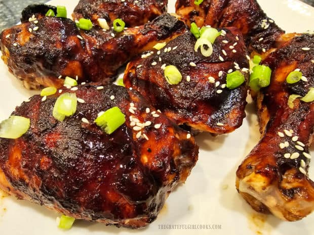Baked Asian BBQ-Glazed chicken is garnished with green onions and sesame seeds.