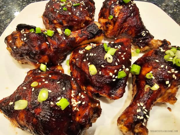 A white platter with six pieces of Asian BBQ-Glazed chicken on it, ready to be enjoyed.