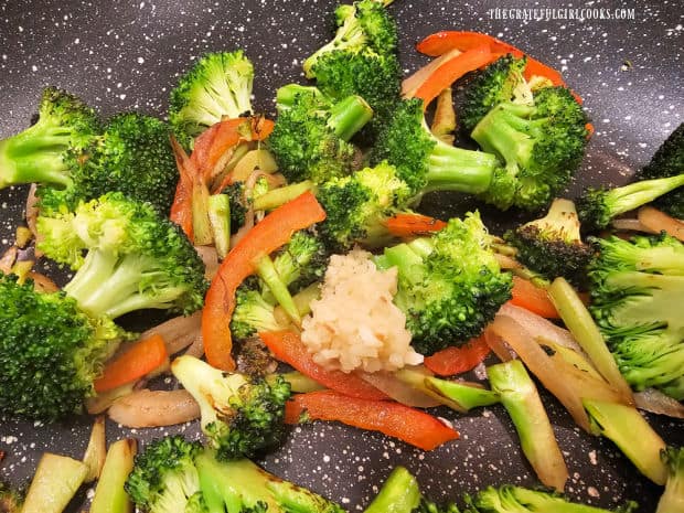 Minced garlic is added to the cooked vegetables in the skillet and cooked for 1 minute.