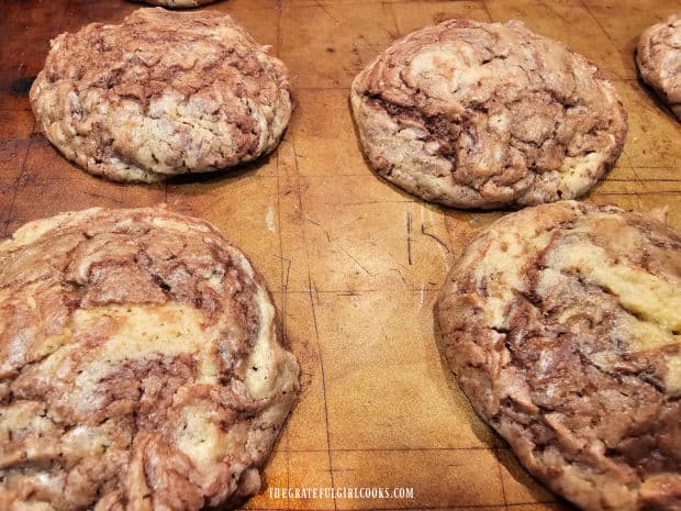Some chocolate swirl cookies cool on the baking sheet after they have finished cooking.