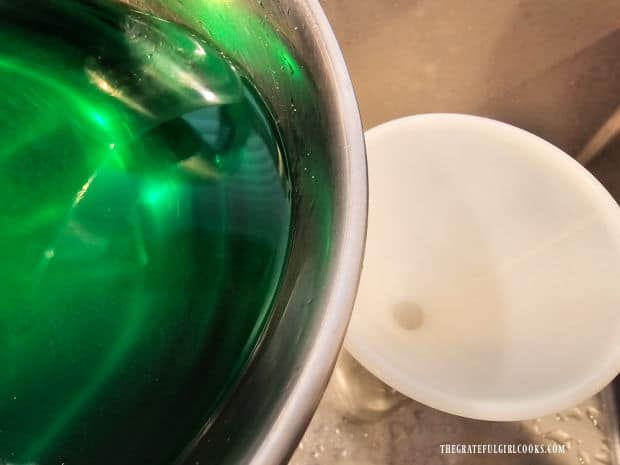 The crème de menthe is poured through a funnel into a bottle.