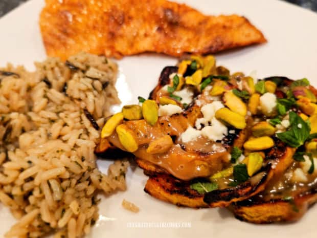  A white plate with a piece of salmon, wild rice and Mediterranean butternut squash is served.