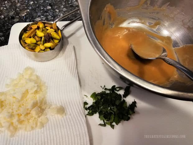 Pistachios, crumbled feta, chopped mint and tahini dressing ready to garnish baked squash.