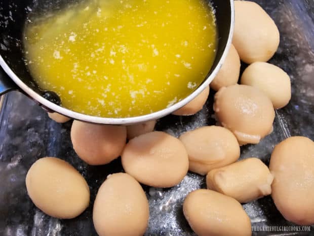 Melted butter is drizzled over all the potatoes, then they're tossed to coat.