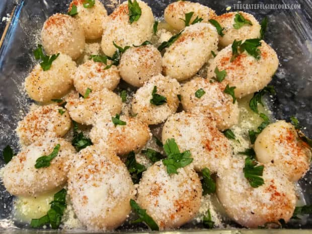 Paprika is sprinkled on top of the potatoes, then chopped parsley is added.