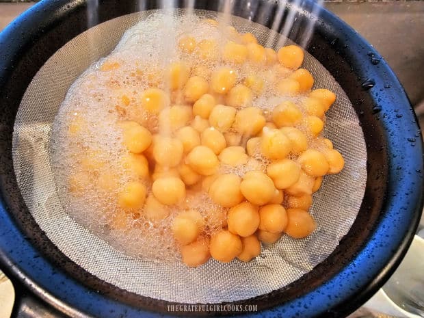 A can of garbanzo beans (chickpeas) is rinsed and drained before making hummus.