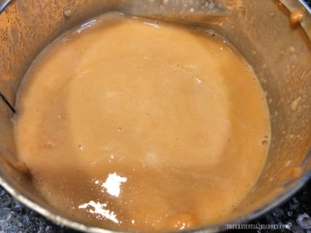 A can of tahini sesame paste is stirred well to create a creamy consistency.