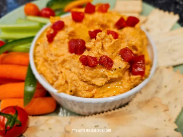 The hummus is served with crackers, and fresh chopped veggies.