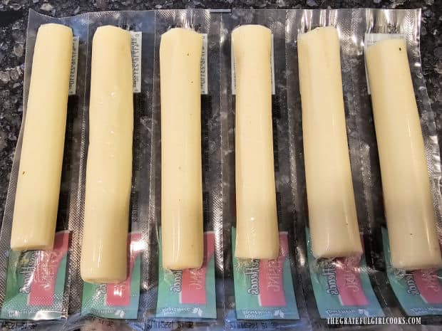 6 sticks of mozzarella string cheese are removed from wrappers and cut in half.