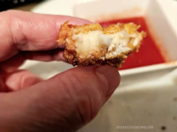 The melted mozzarella inside is shown after a bite has been taken.