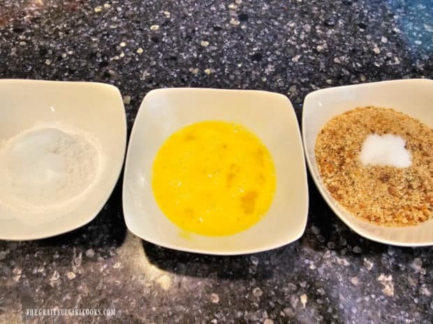 Three bowls with ingredients for the breading of mozzarella sticks for air-frying.