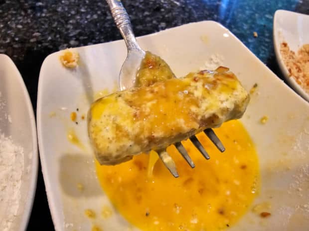 The floured cheese is coated in an egg mixture.