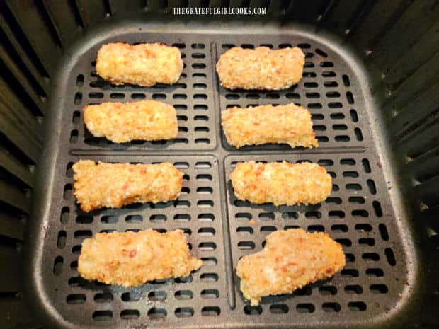 Eight mozzarella bites are cooked in air fryer basket in a single layer.