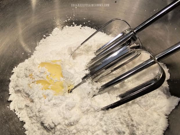 Powdered sugar and butter are beaten together using an electric mixer.
