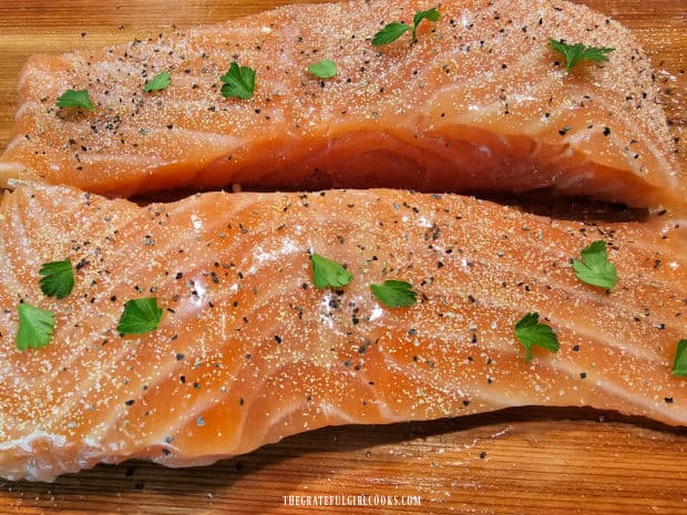 The seasoned salmon fillets rest on a soaked cedar plank before grilling.
