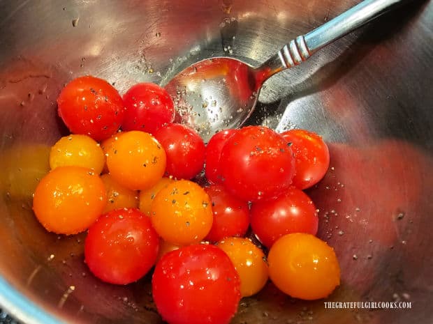 Colorful cherry tomatoes are covered with olive oil and spices before grilling.