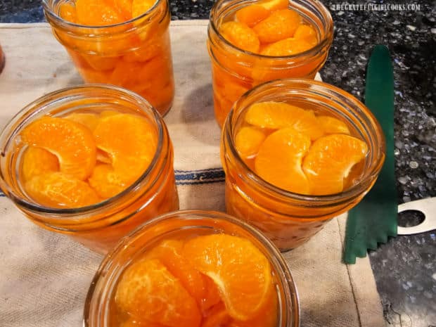 Jars are filled with mandarin orange segments, then syrup is added, to fill.