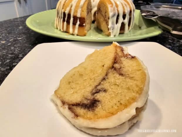 A slice of Instant Pot Cinnamon Bundt Cake on a white plate, with cake in the background.