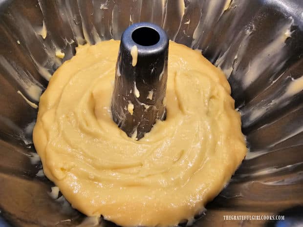 Half the cake batter is spread into the buttered bundt pan.