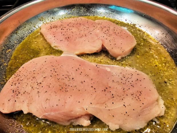 Boneless skinless chicken breasts are seasoned then laid in skillet with lemon garlic sauce.