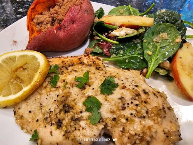 Lemon garlic baked chicken is served with a sweet potato and a small salad on the side.