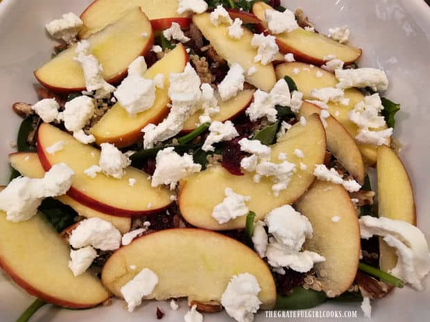 Goat cheese crumbles and thinly sliced apples are added to the salad.