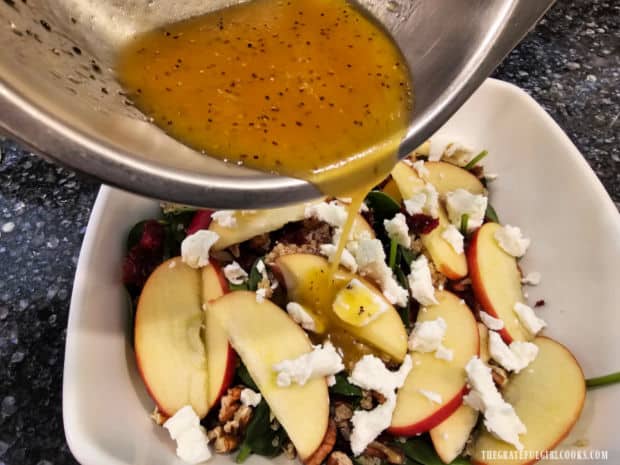 Lemon dressing is poured over the Spinach Apple Quinoa Salad before combining.