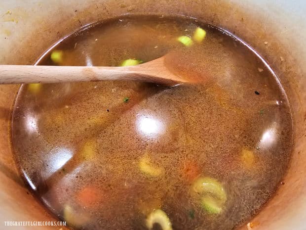 Veggie broth, tomato paste and water are added to the soup.