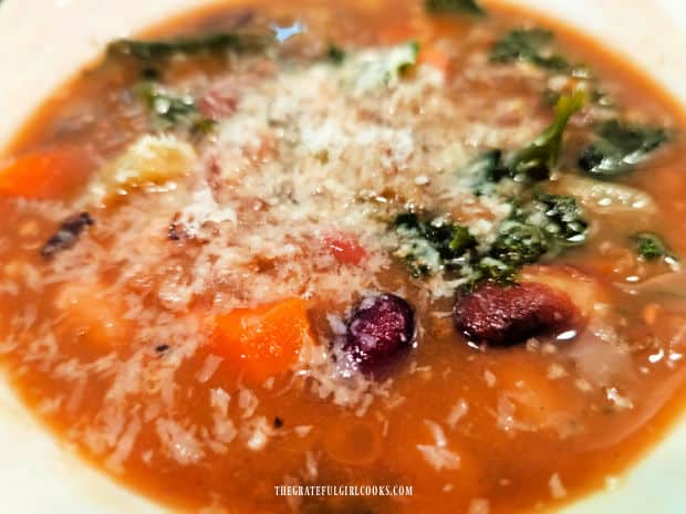 Bean and Kale Soup is served hot, garnished with finely grated Parmesan cheese.