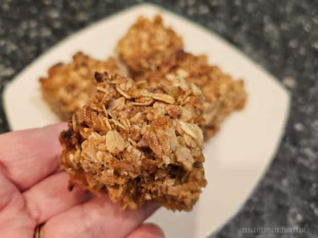 Holding one of the crunchy oatmeal marmalade bars over a white plate.
