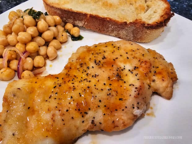 Skillet chicken and garbanzo salad is served with garlic bread on a white plate.