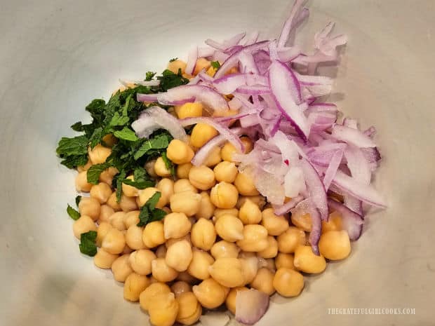 Drained garbanzo beans are mixed with fresh chopped mint and thinly sliced red onions.