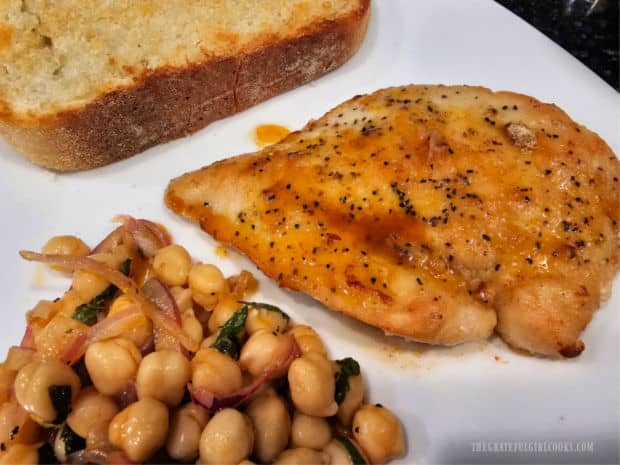 Garlic bread accompanies the skillet chicken and garbanzo salad on the plate.