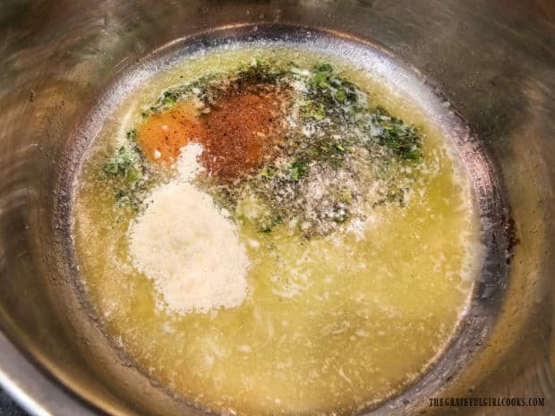 Spices and Parmesan are added to melted butter in saucepan.