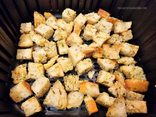 Air fryer basket with seasoned croutons, ready to cook.