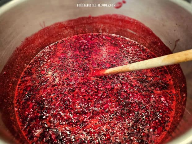 A canner full of berries, pectin and sugar is brought to a boil.