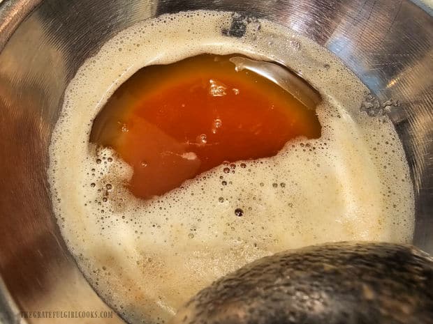 Foam is moved to the side revealing color of the browned butter in the saucepan.